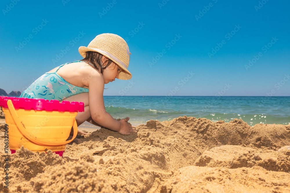 Child wearing protective sunhat playing on a beach Child wearing protective sunhat playing on a beach