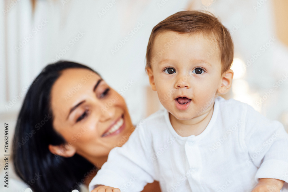 A beautiful young woman in a white top and black leggings holds her little son in a black short A beautiful young woman in a white top and black leggings holds her little son in a black short