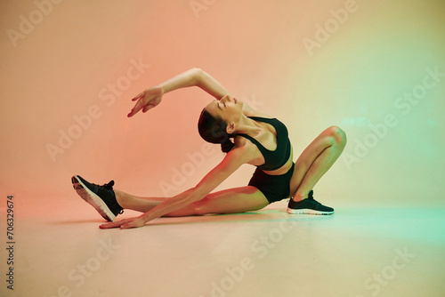 Showing flexibility. Young fitness woman in sportive clothes against background in studio