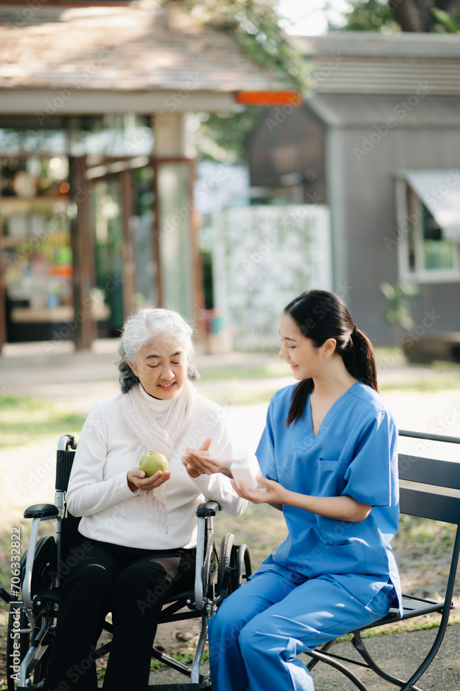 Elderly asian senior woman on wheelchair with Asian careful caregiver and encourage patient, walking in garden. with care from a caregiver. and senior health insurance Elderly asian senior woman on wheelchair with Asian careful caregiver and encourage patient, walking in garden. with care from a caregiver. and senior health insurance