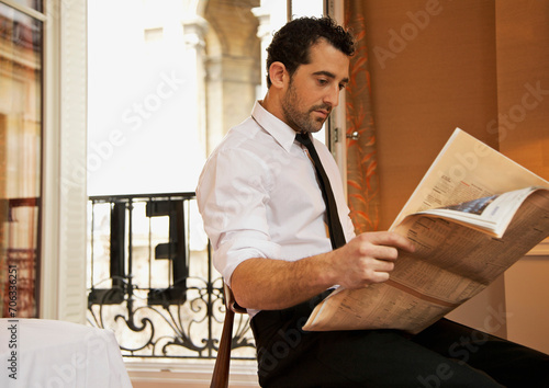 Businessman in hotel room reading newspaper
 photo
