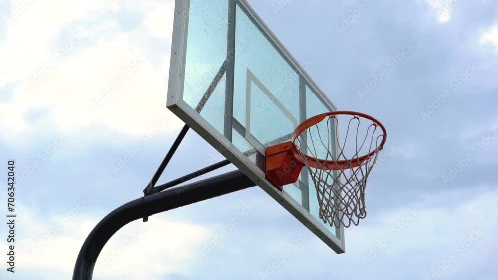 Cloudy rainy day leaves basketball backboard and net wet and dripping with water. No games in the city today due to the weather. Courts are closed. Cloudy rainy day leaves basketball backboard and net wet and dripping with water. No games in the city today due to the weather. Courts are closed.