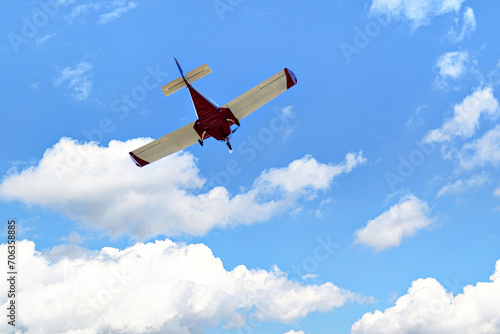 Single engine ultralight plane flying in the blue sky with white clouds photo