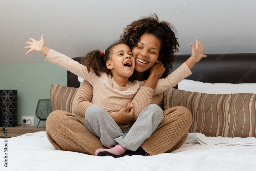 Togetherness Concept. Cheerful african american mother and daughter playing together on bed Togetherness Concept. Cheerful african american mother and daughter playing together on bed