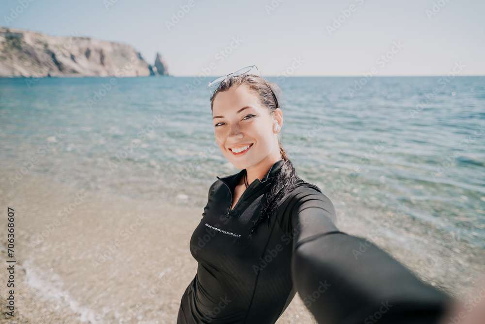 Woman summer travel sea. Happy tourist enjoy taking selfie photo outdoors for memories. Woman traveler posing on the beach at sea surrounded by volcanic mountains, sharing travel adventure journey Woman summer travel sea. Happy tourist enjoy taking selfie photo outdoors for memories. Woman traveler posing on the beach at sea surrounded by volcanic mountains, sharing travel adventure journey