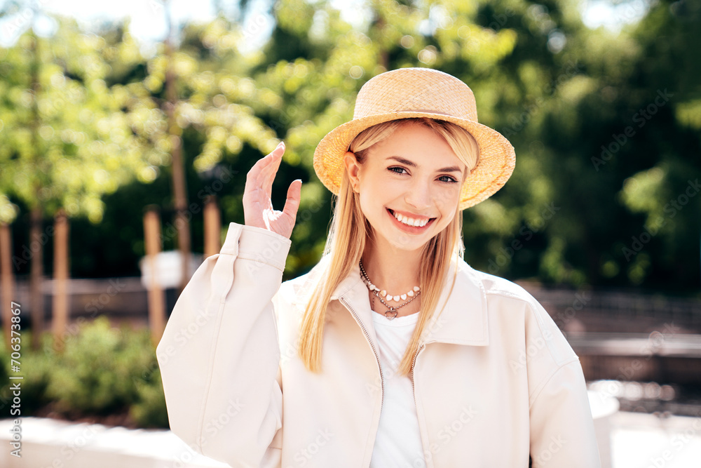 Young beautiful smiling blond woman in trendy summer clothes. Carefree female posing on the street background at sunny day. Positive model outdoors at sunset. Cheerful and happy in hat. Natural makeup