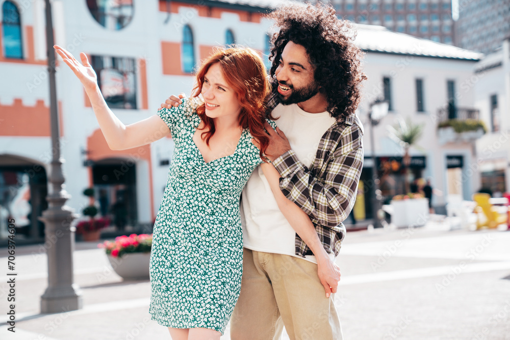 Naklejka premium Smiling beautiful redhead woman and her handsome boyfriend. Model in casual summer clothes. Happy cheerful family. Female having fun. Couple posing in the street at sunny day
