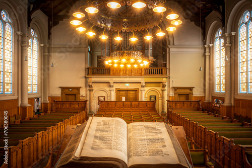 Open Bible book placed in the center of a wooden pew-filled church photo