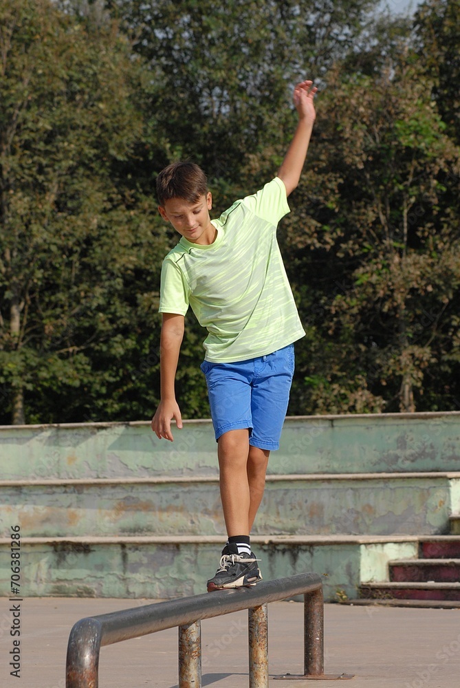 playful kid walking balancing on a metal tube on urban park background.