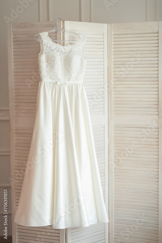 A white dress hangs delicately on a white door, exuding ethereal beauty and capturing the essence of pure aesthetics.