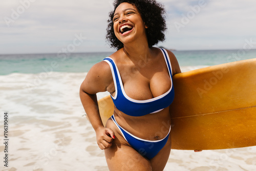 Happy, curvy woman enjoying a summer surfing adventure at the beach