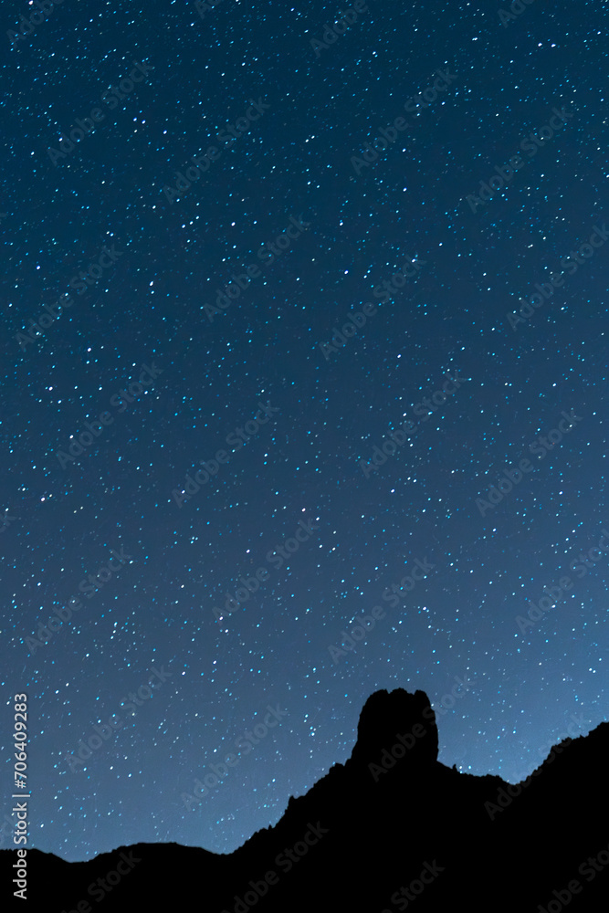 Beautiful vertical night astrophotography photograph with a clear, starry sky and a silhouetted mountain in the Teide National Park, in Tenerife, Canary Islands, Spain, Europe