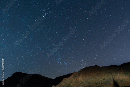 Beautiful astrophotography night landscape with a clear and starry sky, with an illuminated and silhouetted mountain in the Teide National Park, in Tenerife, Canary Islands, Spain, Europe