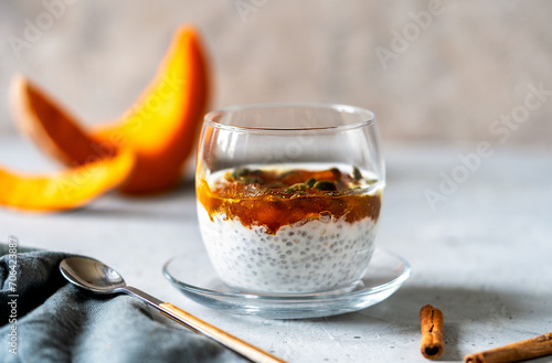 Spiced Pumpkin Chia Parfait in a glass with ingredients over grey background