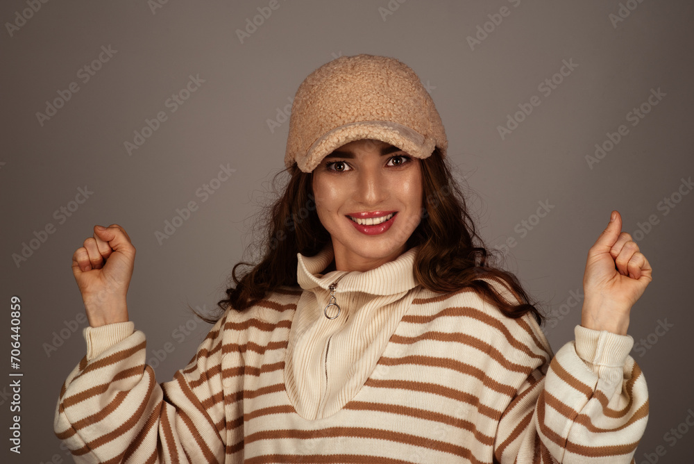 A young beautiful girl of European appearance on a monotonous background wearing mittens and a hat A young beautiful girl of European appearance on a monotonous background wearing mittens and a hat