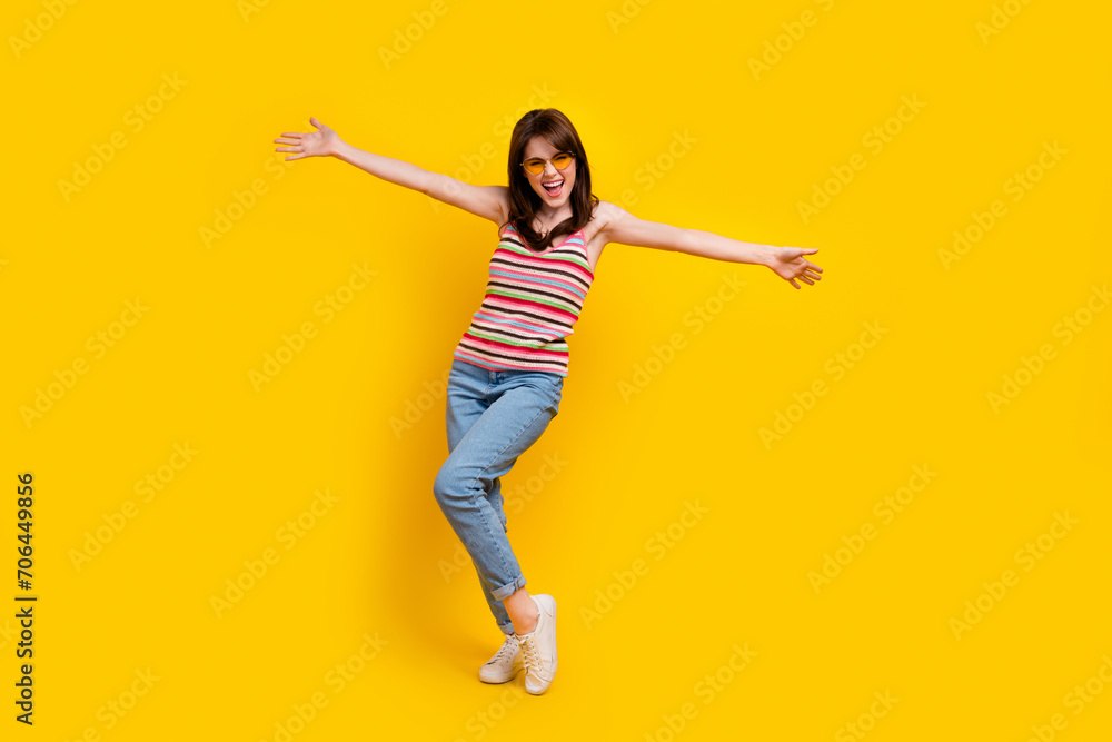 Full body photo of funny pleasant cheerful girl wear striped tank denim trousers presenting herself isolated on yellow color background.