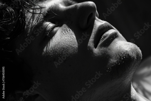 A black and white photo capturing a man with his eyes closed. Can be used to depict relaxation, meditation, or introspection