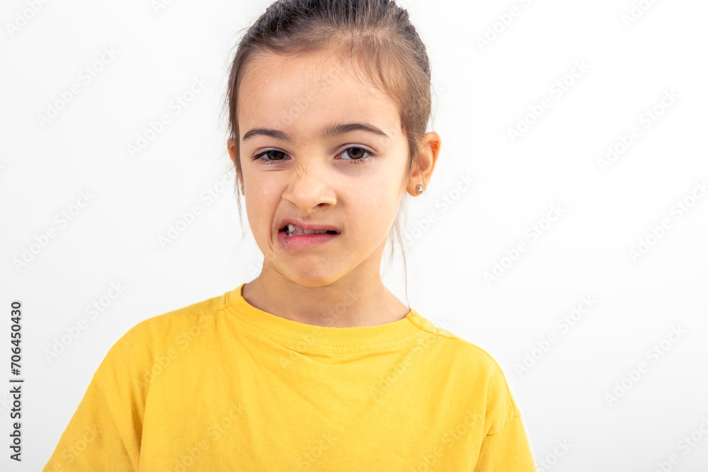 A little girl grimaces with displeasure on a white background, isolated. A little girl grimaces with displeasure on a white background, isolated.