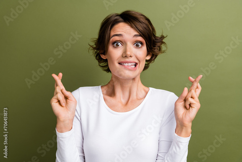 Photo portrait of lovely young lady crossed fingers excited bite lips dressed stylish white garment isolated on khaki color background