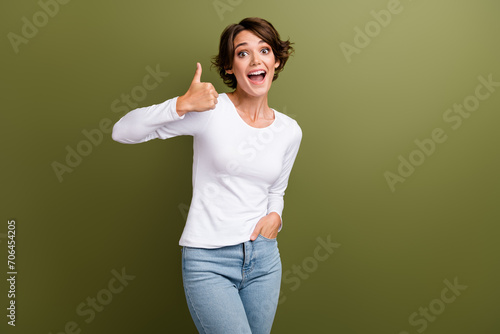 Portrait of amazed cheerful girl raising thumb finger up expressing positive attitude agreement isolated khaki green color background