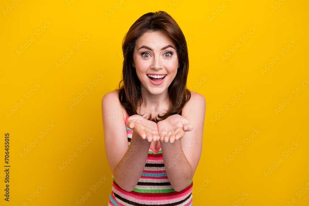 Portrait of pleasant impressed cute woman with piercing wear knit tank hold object on arms isolated on vivid yellow color background Portrait of pleasant impressed cute woman with piercing wear knit tank hold object on arms isolated on vivid yellow color background