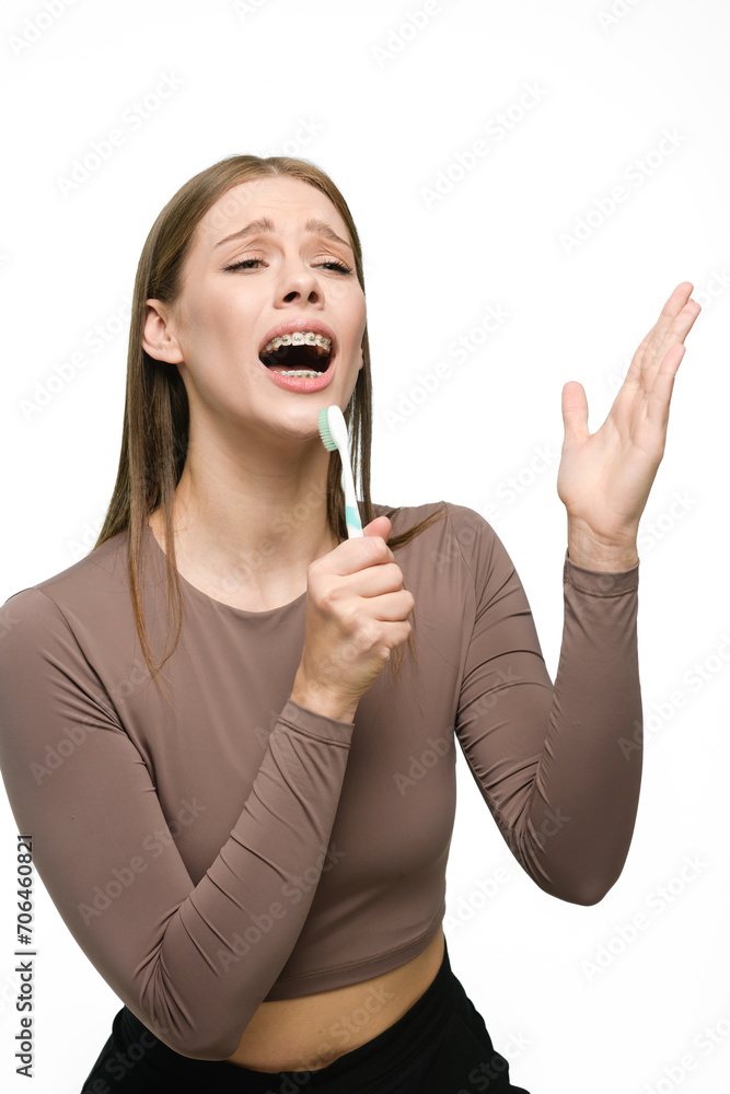 Young beautiful woman singing to toothbrush isolated on white background Young beautiful woman singing to toothbrush isolated on white background