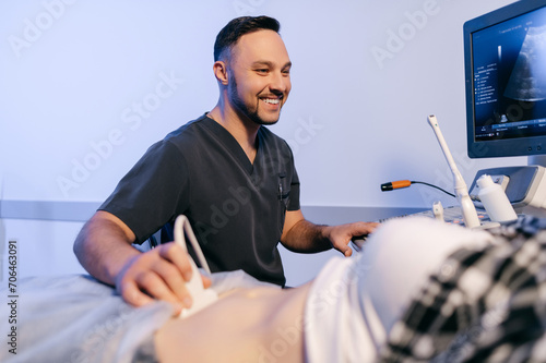 A male doctor performs an abdominal ultrasound on a female patient in the clinic. Pregnant woman at a gynecologist's appointment.