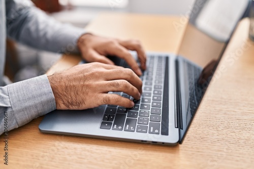 Young hispanic man using laptop at office