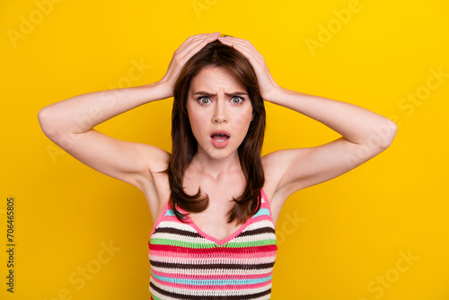 Photo of speechless girl with stylish hairdo wear striped tank keep arms on head staring open mouth isolated on yellow color background