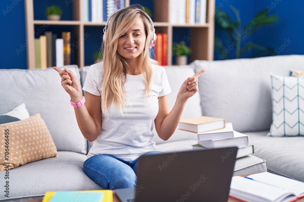 Young blonde woman studying using computer laptop at home smiling confident pointing with fingers to different directions. copy space for advertisement Young blonde woman studying using computer laptop at home smiling confident pointing with fingers to different directions. copy space for advertisement