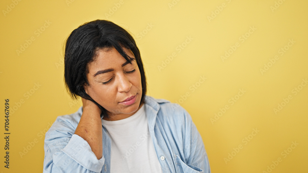 Hispanic adult woman with neck pain against yellow background Hispanic adult woman with neck pain against yellow background