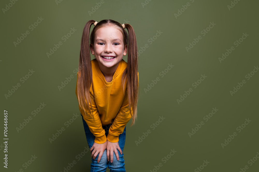 Portrait of adorable small kid with tails dressed yellow sweatshirt hands on knees smiling to you isolated on khaki color background Portrait of adorable small kid with tails dressed yellow sweatshirt hands on knees smiling to you isolated on khaki color background