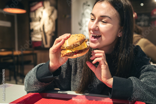 An appetizing chicken burger in female hands in a fast food restaurant.