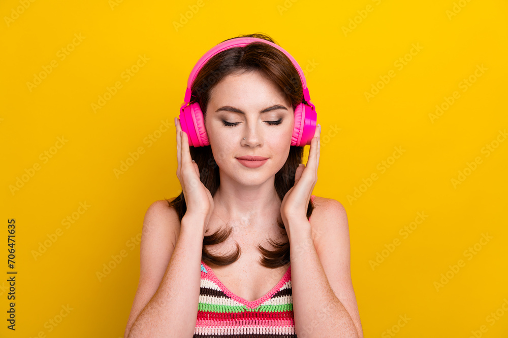 Portrait of pleasant woman with piercing wear knit tank touch earphones enjoy calm music isolated on vivid yellow color background Portrait of pleasant woman with piercing wear knit tank touch earphones enjoy calm music isolated on vivid yellow color background