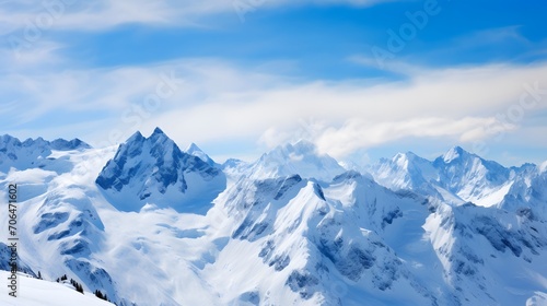 Panoramic view of snow covered mountains under blue sky with clouds © A