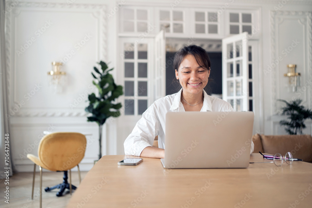 Smiling woman working on laptop in a bright, stylish interior, exuding professional joy. Smiling woman working on laptop in a bright, stylish interior, exuding professional joy.