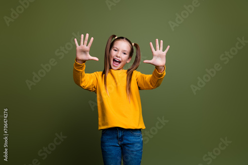 Portrait of clever smart kid with tails hairstyle dressed yellow sweatshirt showing palms count to ten isolated on khaki color background