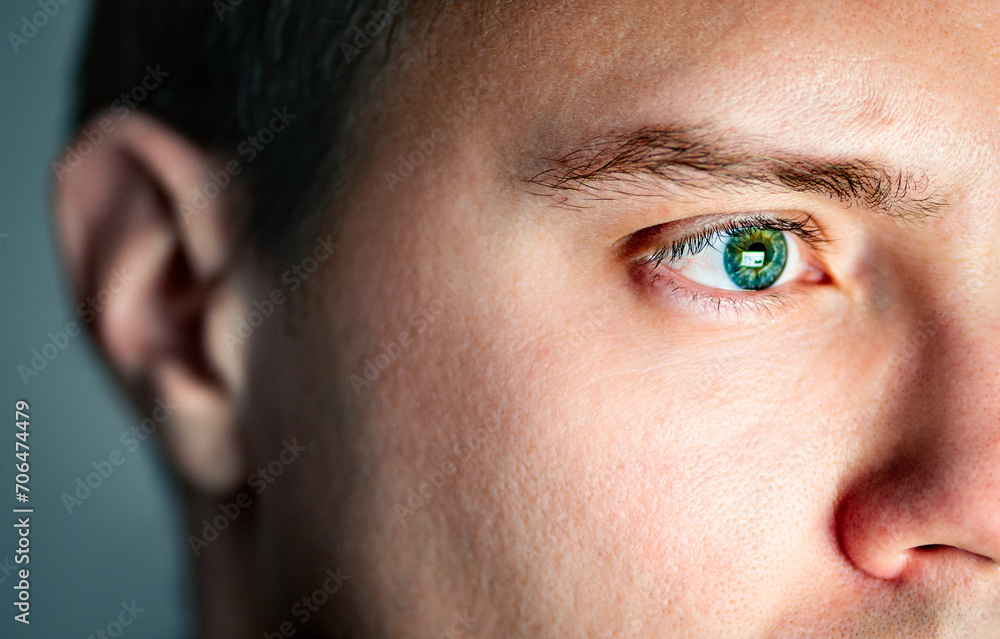 Obraz premium Eye and ear. See and hear. Senses concept. Skin with pore. Closeup of face of a man. Computer screen light reflect from green eye. Deaf person or bad eyesight. Autism or adhd. Sound and sight health.