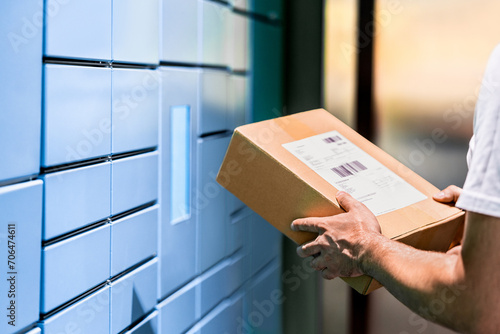 Parcel locker and package delivery service machine. Collect packet at mail storage station at post office. Man holding a box in hand. Blue shipment terminal automat pick up. Courier or customer.