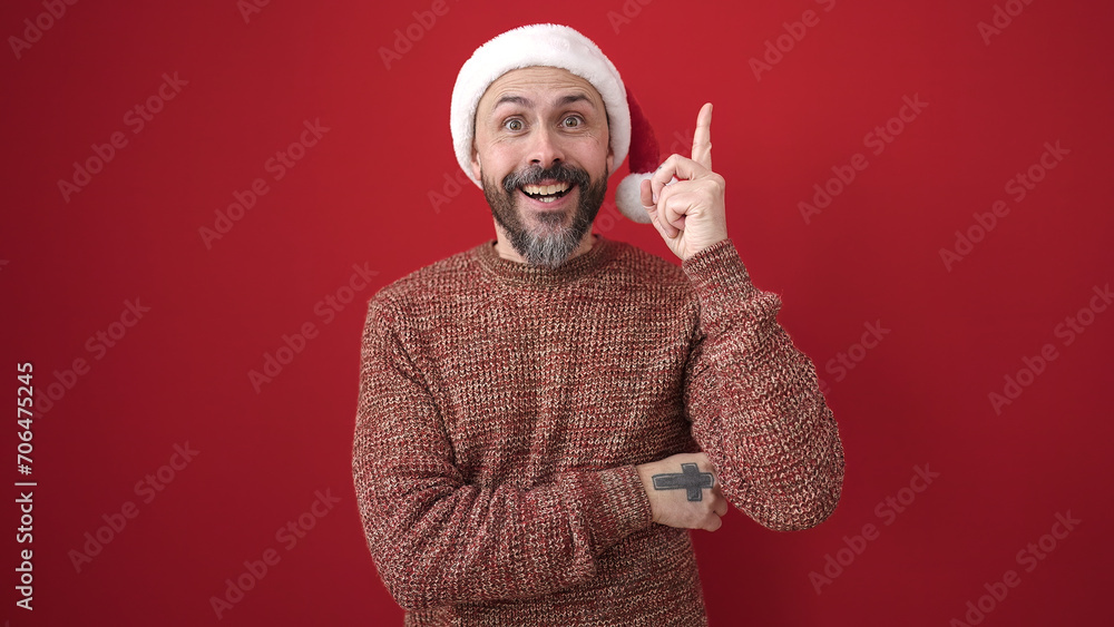 Young bald man wearing christmas hat with idea expression over isolated red background Young bald man wearing christmas hat with idea expression over isolated red background