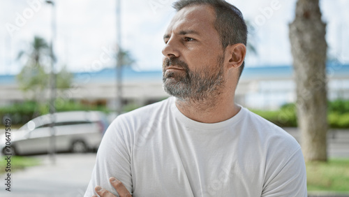 Handsome mature hispanic man with grey hair in a city setting, reflecting a sense of contemplation.