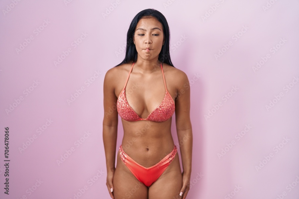 Hispanic woman wearing bikini making fish face with lips, crazy and comical gesture. funny expression. Hispanic woman wearing bikini making fish face with lips, crazy and comical gesture. funny expression.
