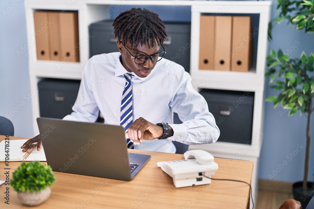 African american man business worker using laptop looking watch at office African american man business worker using laptop looking watch at office