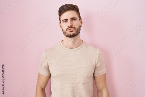 Hispanic man with beard standing over pink background looking at the camera blowing a kiss on air being lovely and sexy. love expression.