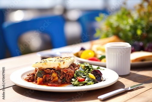 moussaka plated with a greek salad on a sunny outdoor table photo