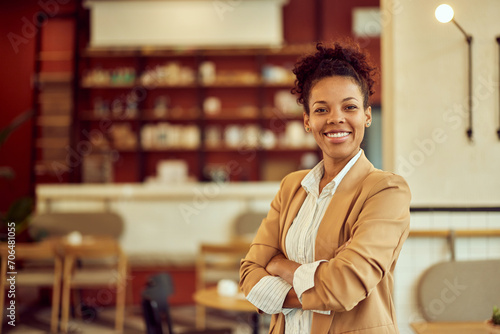 Portrait of a smiling African woman, holding her hands crossed, posing for the camera.