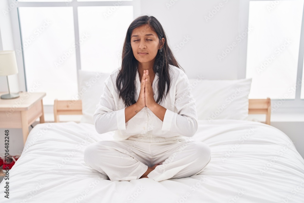 Young beautiful hispanic woman doing yoga exercise sitting on bed at bedroom Young beautiful hispanic woman doing yoga exercise sitting on bed at bedroom