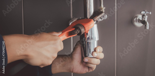 plumber at work in a bathroom, plumbing repair service , fix water plumbing leaks, replace the kitchen sink drain photo