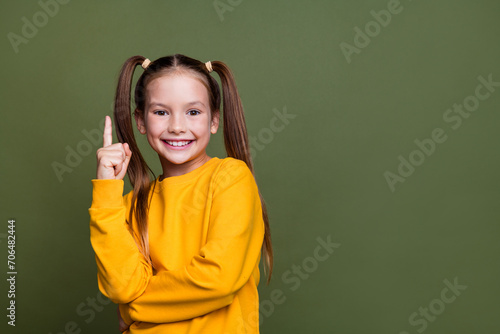 Portrait of smart clever small kid with tails dressed yellow sweatshirt raising finer up has idea isolated on khaki color background © deagreez