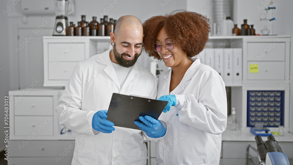 Fototapeta premium Two smiling scientists in the lab, engrossed in a lively chat while scrutinizing documents on clipboard